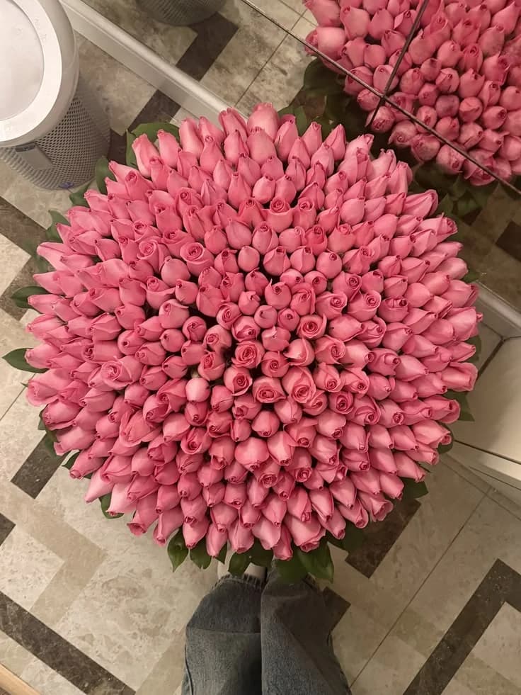 A round bouquet of pink roses photographed from above on a patterned tile floor